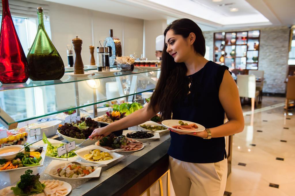 Grand Mercure Majlis Residences Abu Dhabi Exterior foto A woman selecting food from a buffet